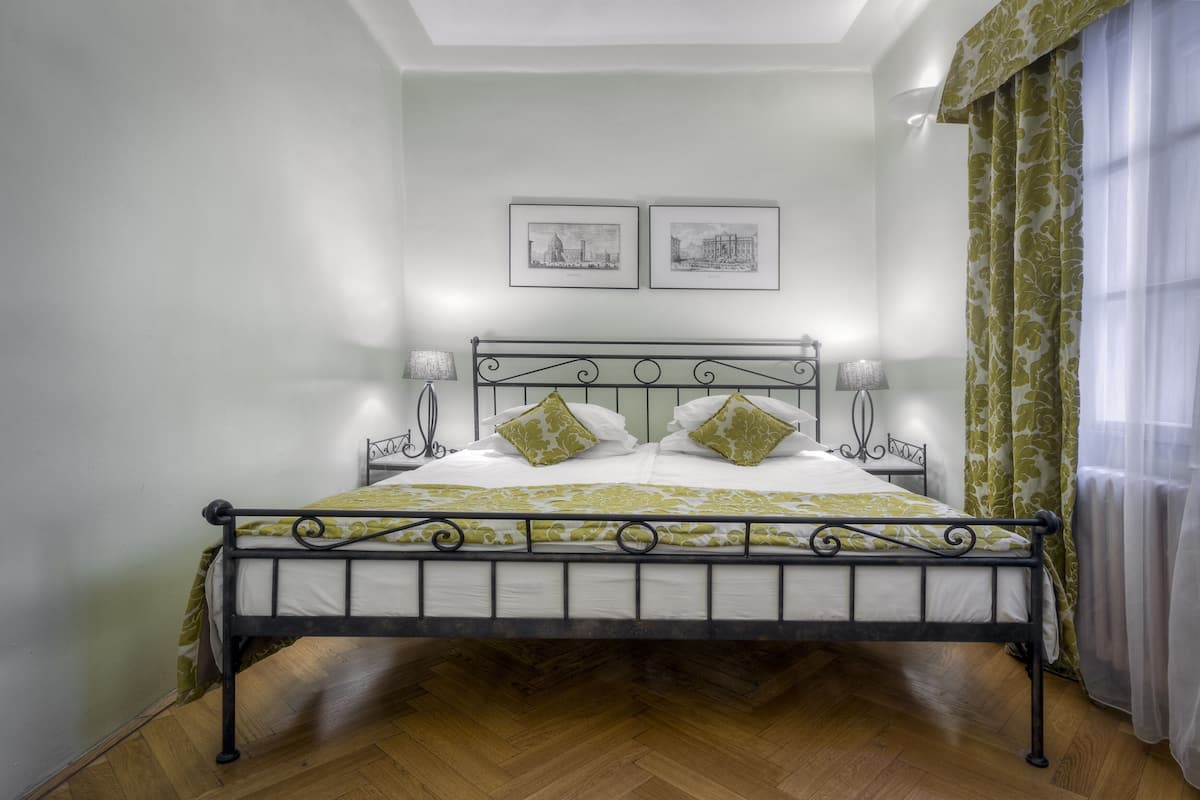 A bed with a metal frame, two pillows, and a green and white bedspread.