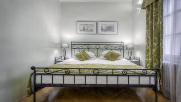 A bed with a metal frame, two pillows, a headboard, and a wall with two framed pictures.