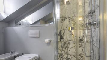 A modern bathroom with a glass-enclosed shower, a toilet, and a sink.