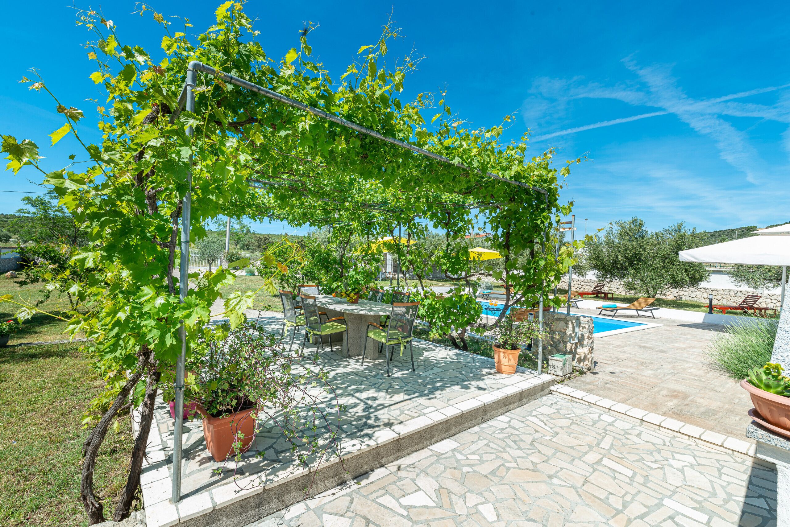 Un'area patio con un pergolato, posti a sedere all'aperto e una piscina.