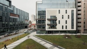 A modern building with large windows and a flat roof, surrounded by a paved area with a few trees and a pedestrian walkway. - Nest Inn Scala (Cluj-Napoca)
