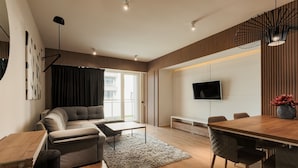 A modern living room with a sofa, coffee table, and dining area. - Nest Inn Scala (Cluj-Napoca)
