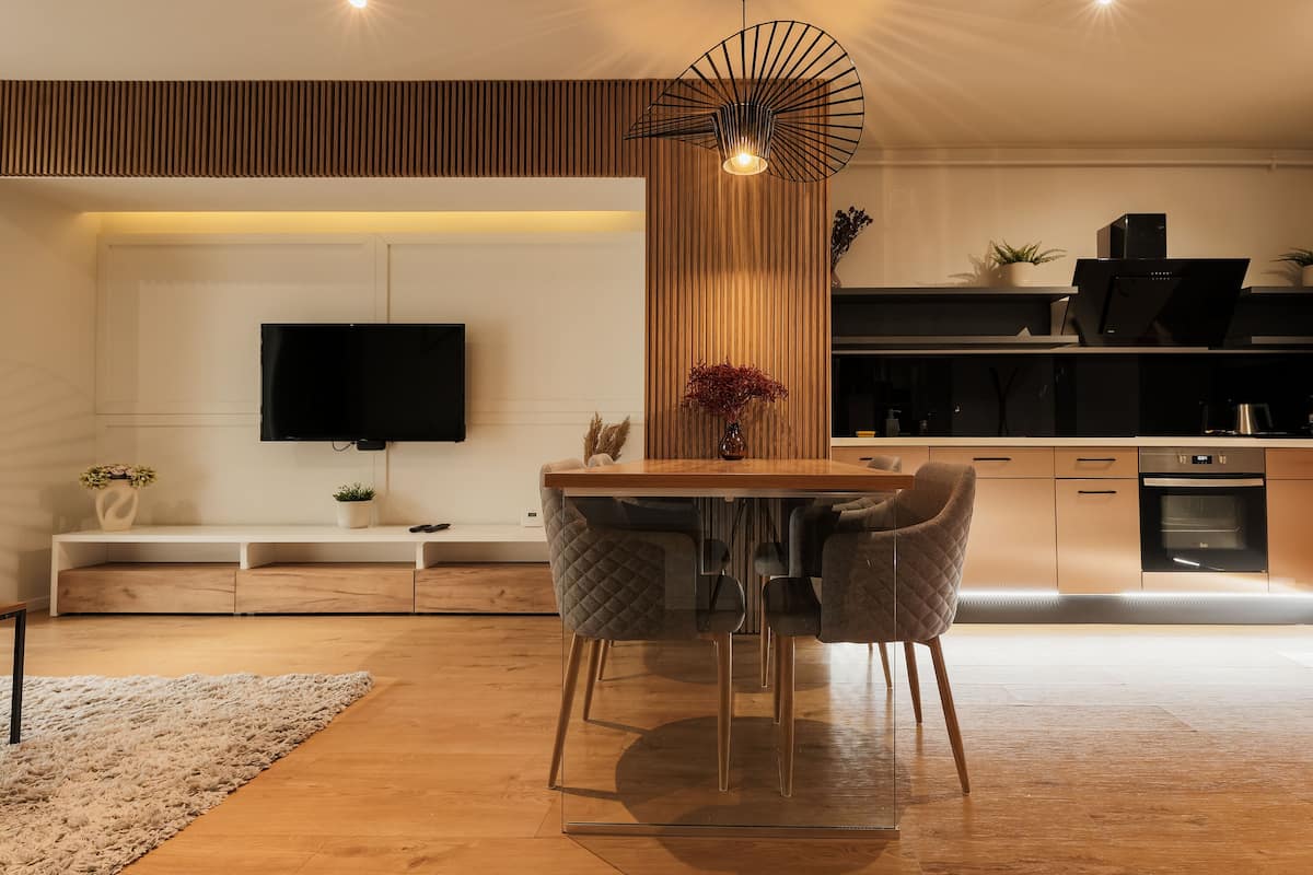 A modern kitchen with a wooden dining table, two chairs, and a built-in oven.