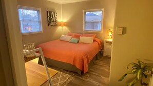 A bedroom with a large bed, two windows, a wall-mounted lamp, a bedside table, and a plant. - Awesome Unbeatable 5-Star Location…walk to ND in 10 minutes! (South Bend)