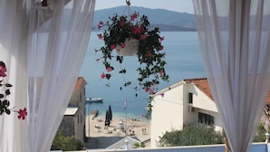 A balcony with a hanging flower pot and a view of the sea and buildings. - Holiday apartment With sea view and terrace (Komarna)