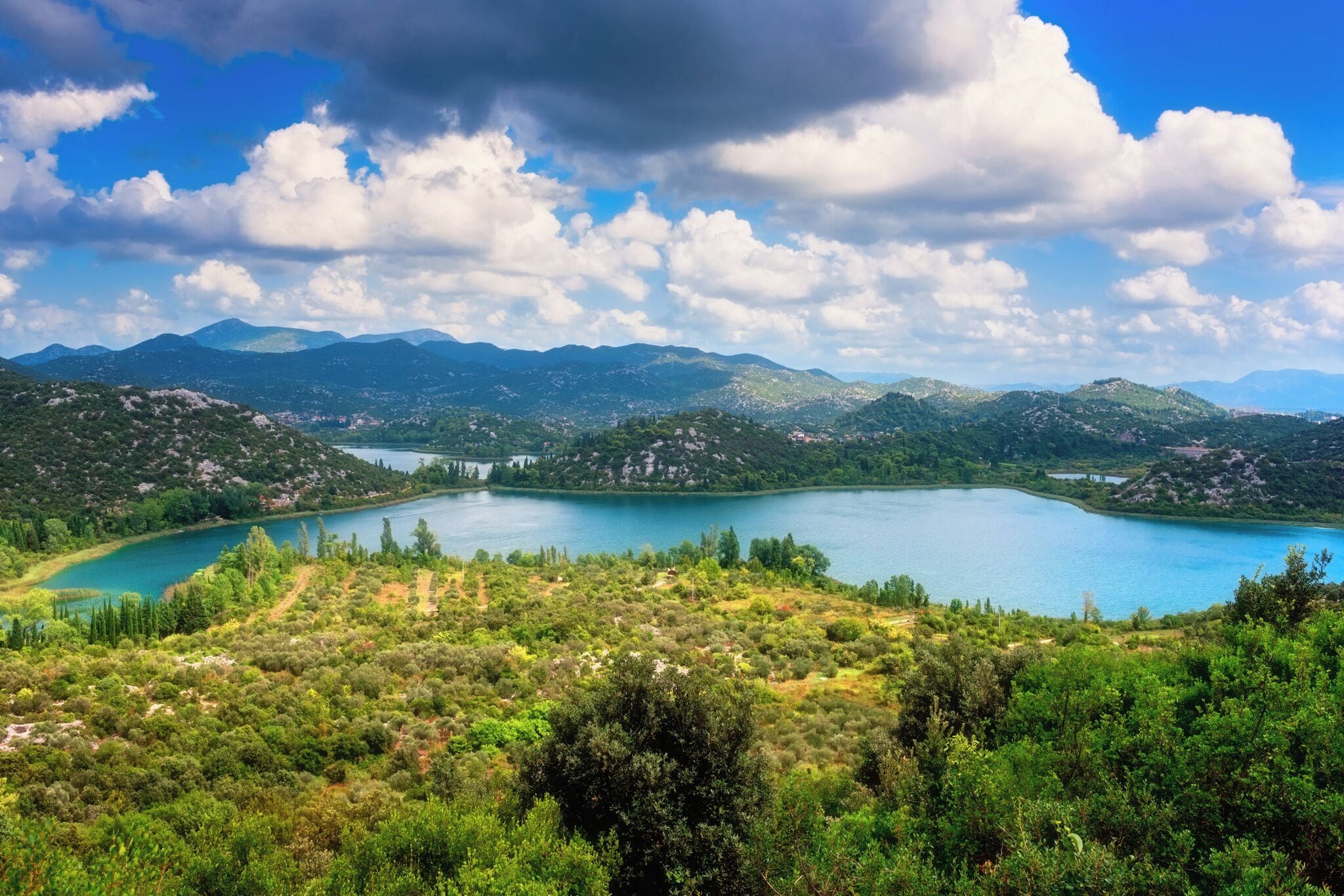 A lake surrounded by mountains and greenery.
