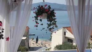 A balcony with a hanging flower pot and a view of the sea and buildings. - Holiday apartment With sea view and terrace (Komarna)