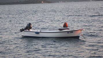Un petit bateau à moteur avec une personne à bord, flottant sur une eau calme.