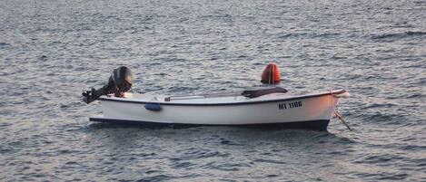 Ein kleines Motorboot mit einer Person an Bord, das auf ruhigem Wasser treibt.