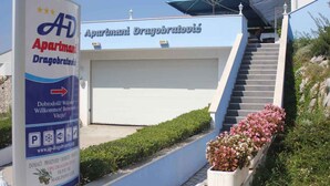 A building with a sign for 'Aparthmani Dragobratovíc' and a staircase leading to the entrance. - Holiday apartment only 50 m from the sea (Komarna)