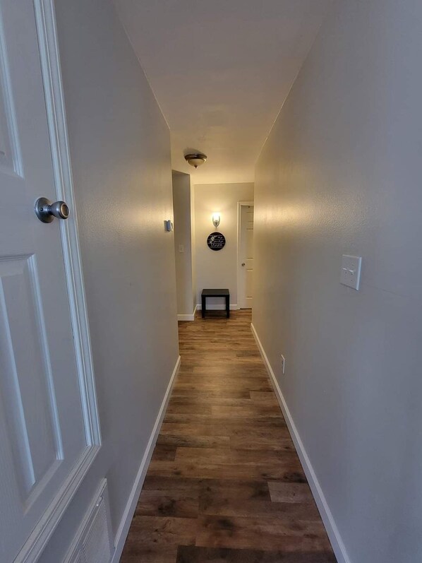 Stylish hallway leads to a door with a wall-mounted light fixture above.