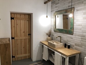 A bathroom with a wooden door, a sink with a marble countertop, and a mirror with a distressed frame. - Alentejo House with Pool (Portel)