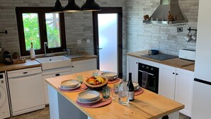 Een moderne keuken met witte kastjes, een houten kookeiland en een groot raam.