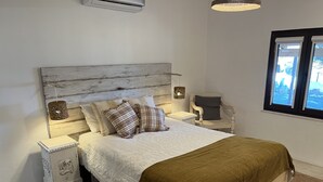 Een slaapkamer met een bed, twee nachtkastjes, een stoel en een raam.