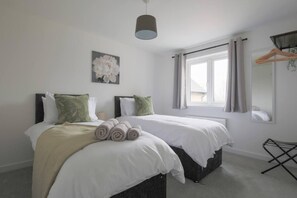 A hotel room with two beds, a large window, a hanging light fixture, and a wall-mounted mirror. - Beautiful 4-bed House 15 Mins to Cardiff & Newport (Cardiff)