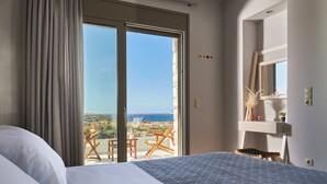 A bedroom with a large bed, a view of the sea, and a balcony with a table and chairs. - Alba Lilia (Πιτσίδια)