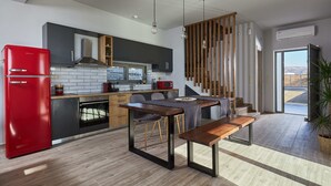 A modern kitchen with a red refrigerator, dark cabinets, and a wooden dining table with benches. - Alba Lilia (Πιτσίδια)