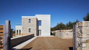 A modern building with a stone facade, a flat roof, and a paved entrance area. - Alba Lilia (Πιτσίδια)