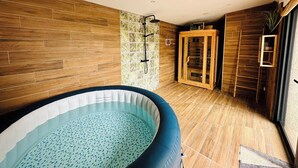 Moderni kylpyhuone, jossa on puulattia, lasiseinäinen sauna ja pieni puhallettava uima-allas.