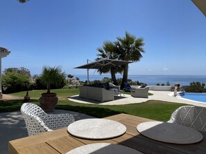 An outdoor patio with a pool, seating area, and a view of the ocean.