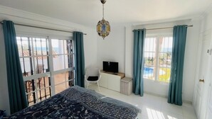 Ein Schlafzimmer mit Bett, Fernseher auf einem Schrank und einem Balkon mit Blick.
