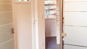 A hallway with a white door, a small window, and a metal gate. - Traumhafte Ferienwohnung vor den Toren Lübecks (Wesenberg)
