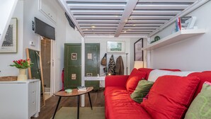 A compact living space with a red sofa, a small table, and a green door. - Cozy studio in Fondazione Prada district (Milano)