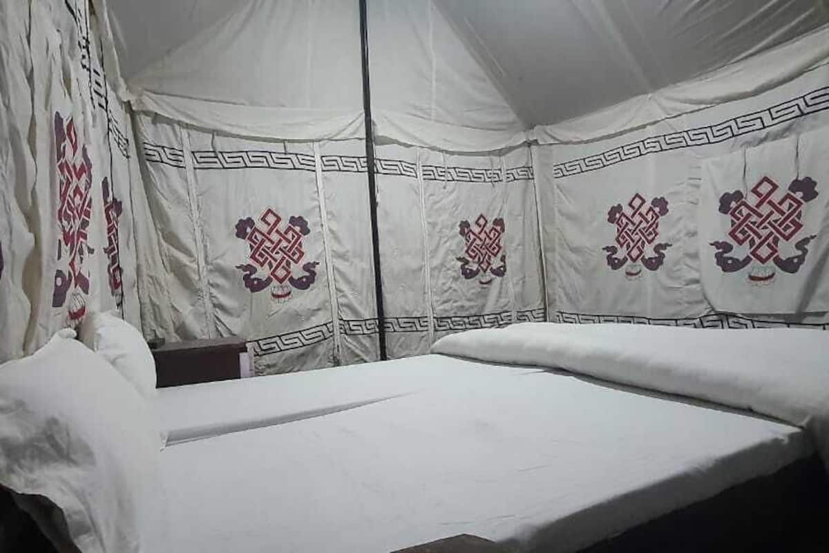 A tent-style room with a bed, pillows, and decorative patterns on the walls.