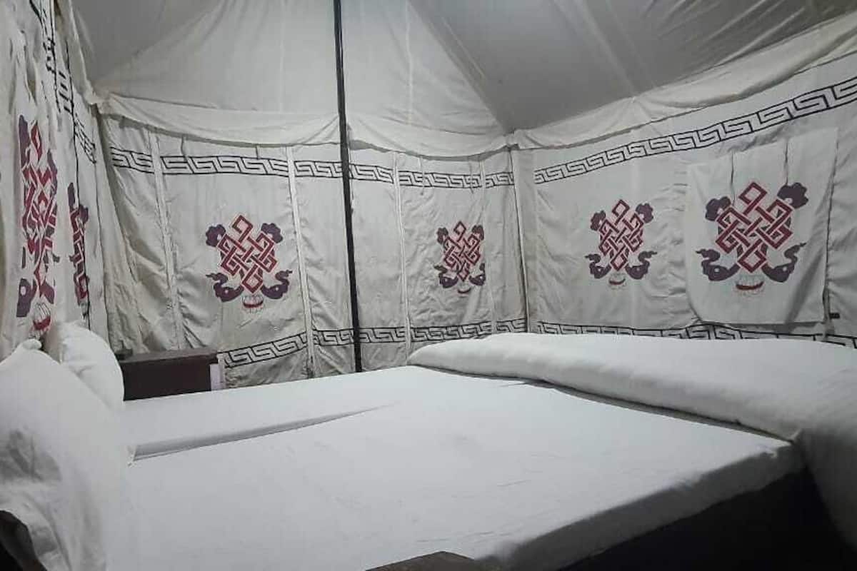 A tent-style room with a bed, pillows, and decorative patterns on the walls.