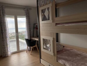 A room with a bunk bed, a desk, and a chair. There is a large window with curtains, and a view of the city. - ZAX SEA VIEW 4 villa complex, Heated pool and 8 bedrooms (ierapetra)