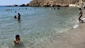 A beach with clear water, rocky cliffs, and people swimming and walking along the shore. - ZAX SEA VIEW 4 villa complex, Heated pool and 8 bedrooms (ierapetra)