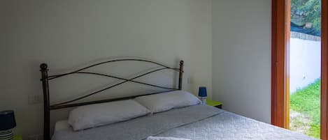 Una cama con cabecera, almohadas y una colcha. Hay dos mesitas de noche con lámparas.