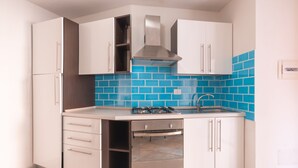 A compact kitchen with white cabinets, a stainless steel range hood, a built-in oven, and a blue-tiled backsplash. - il Girasole (Golfo Aranci)