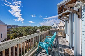 A wooden deck with a table and chairs, overlooking a residential area with houses and trees.