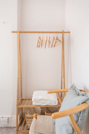 A wooden drying rack with clothes hangers, a basket, and a folded white towel. - Newly renovated large 4/5 bedroom house with garden. (London)