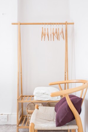 A wooden drying rack with clothes hanging, a wicker basket, and a chair with a cushion. - Newly renovated large 4/5 bedroom house with garden. (London)