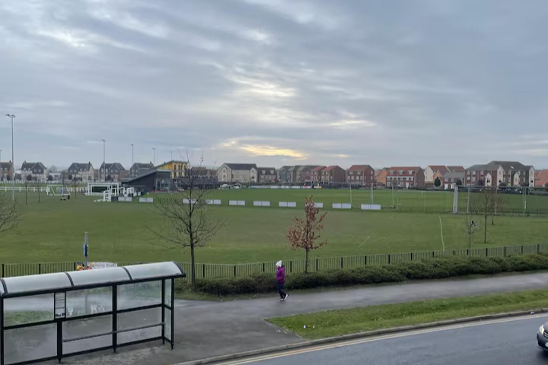 A large open field with a sports field and a bus stop.