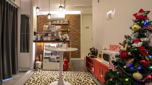 A modern kitchen with a central island, a brick wall, and a Christmas tree. - Bias K-GIRL GUESTHOUSE - Caters to Women (Seoul)