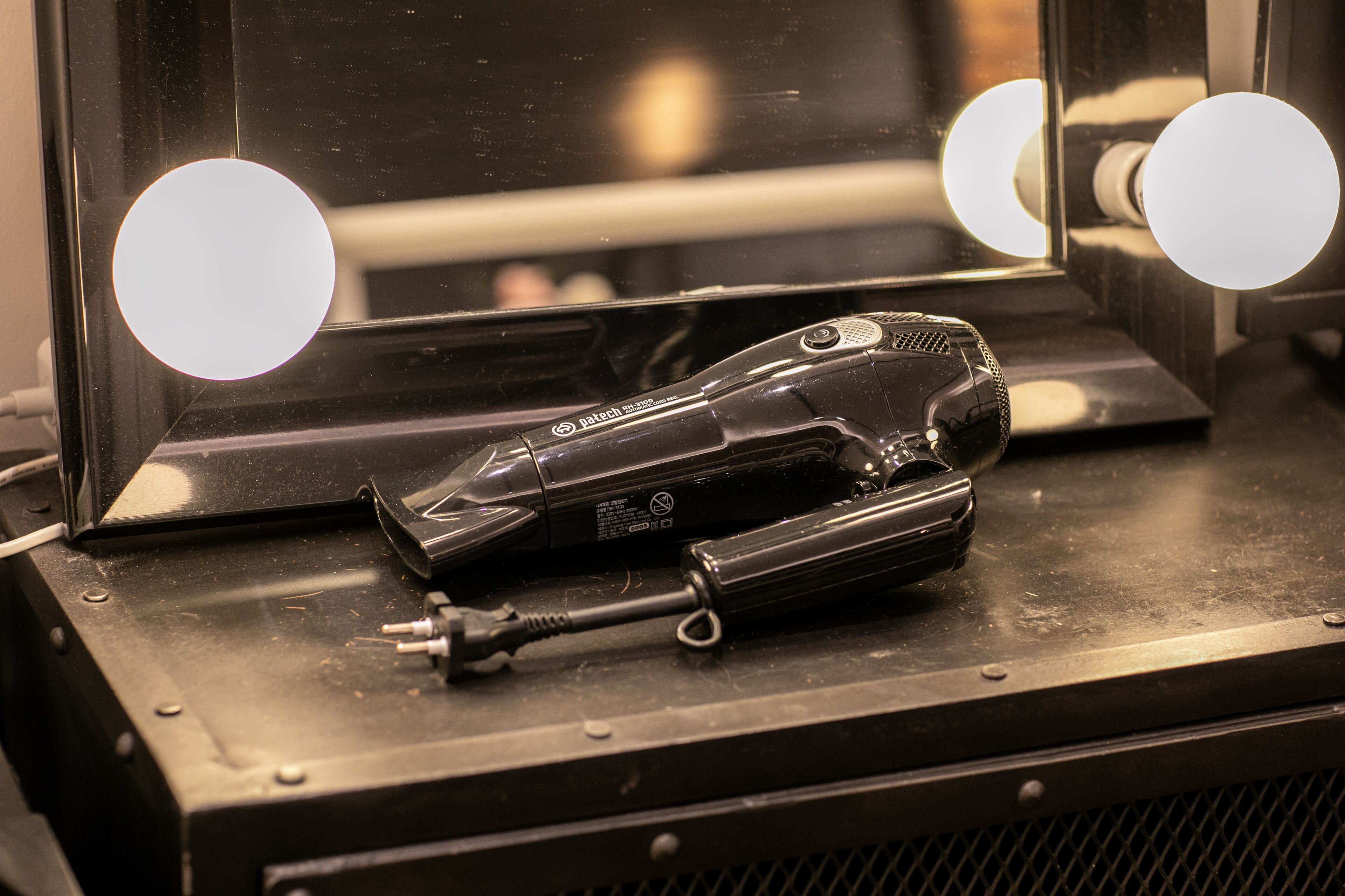 A hair styling tool on a metallic surface with a mirror and lights.