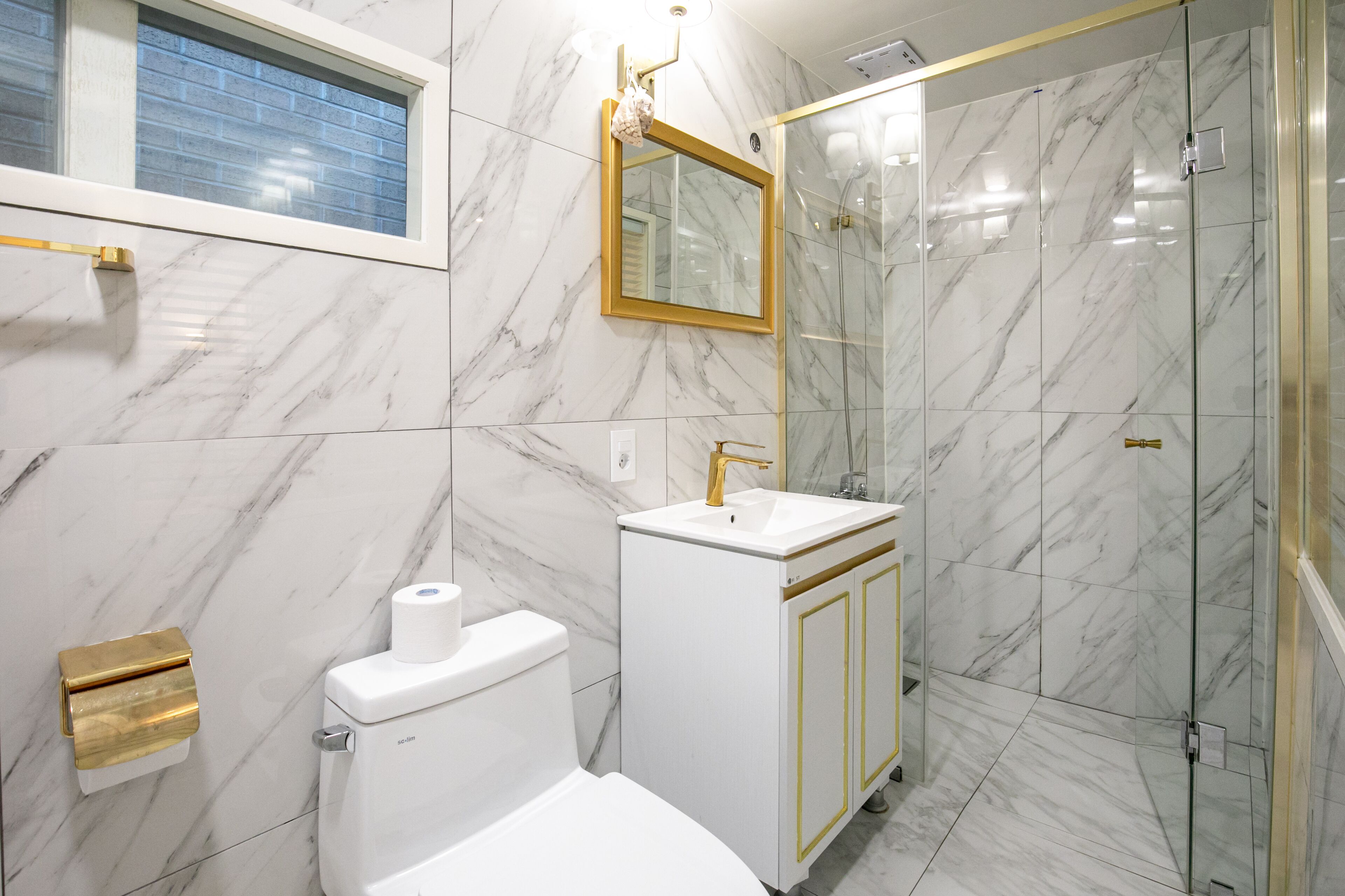 A bathroom with a toilet, sink, and shower.
