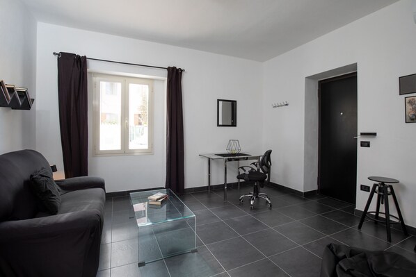 A modern living room with a glass coffee table, a black sofa, a dining table with chairs, and a black door. - Bonaventura's House by Wonderful Italy (Olbia)