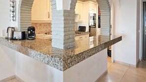 A kitchen with granite countertops, white cabinets, and a microwave.