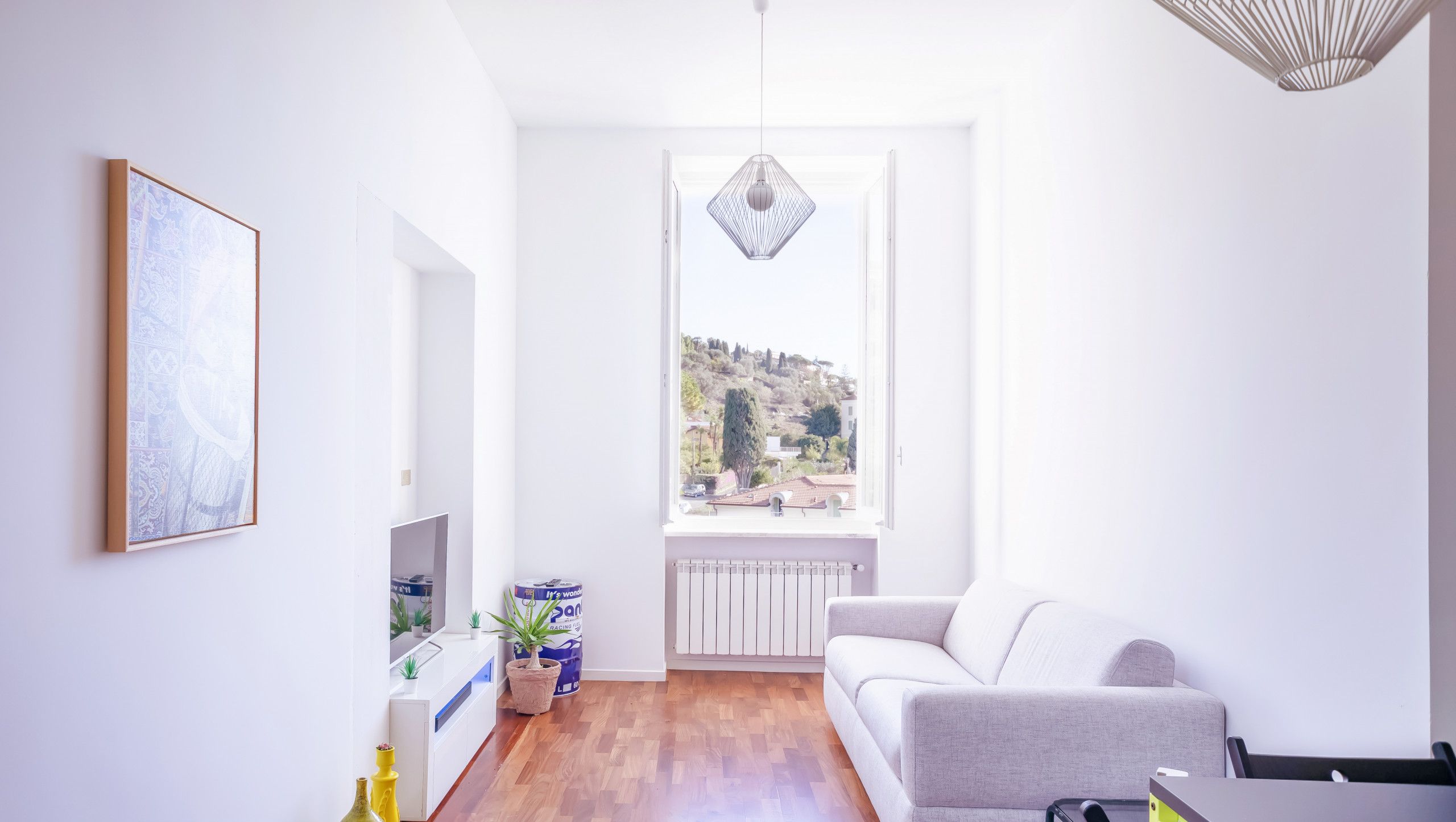 Un salon moderne avec un canapé gris, une table à manger et une vue sur une colline.