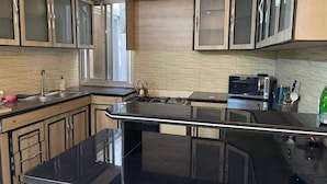 Eine Küche mit schwarzem Arbeitsplatz, Edelstahlgeräten und Holzschränken mit Glastüren.
