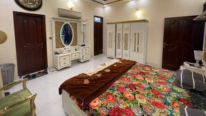 Ein Schlafzimmer mit Bett, Schminktisch, Kommode, Kleiderschrank und Deckenventilator.