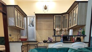 Ein Wohnzimmer mit einem smaragdgrünen Modulsofa, einem Glastisch und einem gemusterten Teppich.