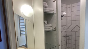 Kylpyhuoneessa on puinen allaskaappi, kaksi pesuallasta, peili ja suihkutila, jonka seinät on laatoitettu.