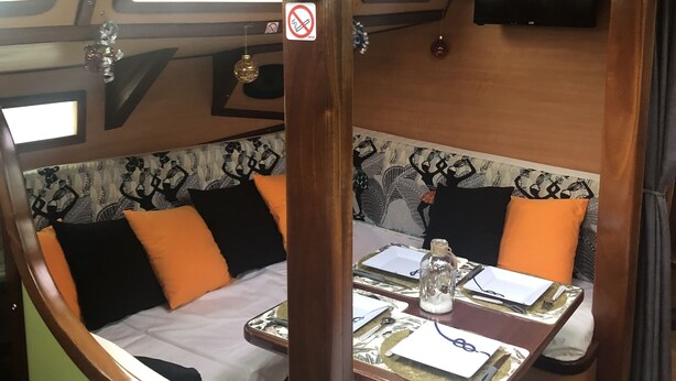 Un intérieur chaleureux avec un coin repas, un banc avec des coussins, une table avec un plateau et une pancarte sur laquelle on peut lire « Bienvenidos ».