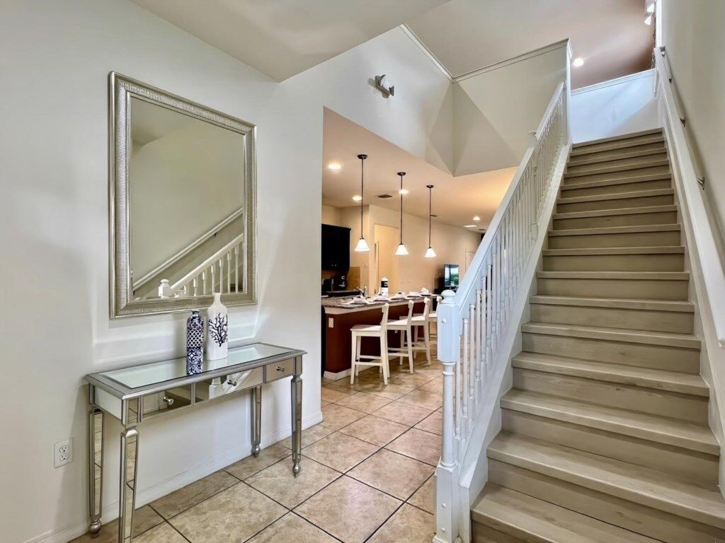 A staircase leading to a dining area with a kitchen in the background.