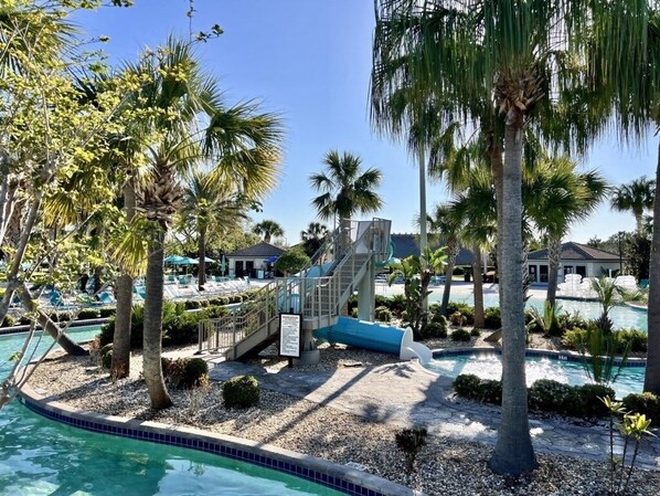 A pool area with palm trees, a slide, and a staircase leading to a building.